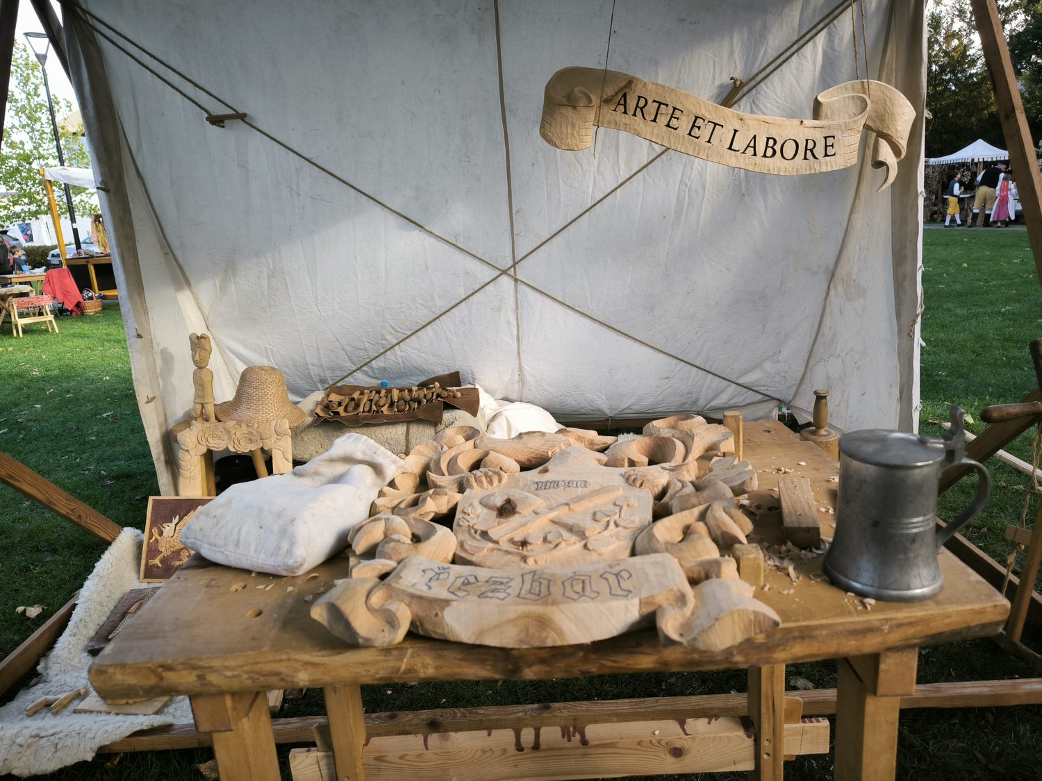 Stůl plný rozpracovaných řezeb pod nápisem Arte et labore